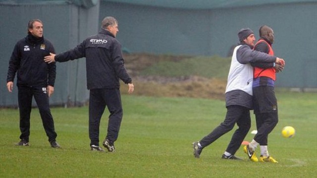 The young Italian striker Mario Balotelli is dragged away by a member of City's coaching staff.