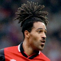 Some of Jason Lee's dreadlocks are pulled into a ponytail on top of his head, and the shorter ones are hanging of the side of his face.