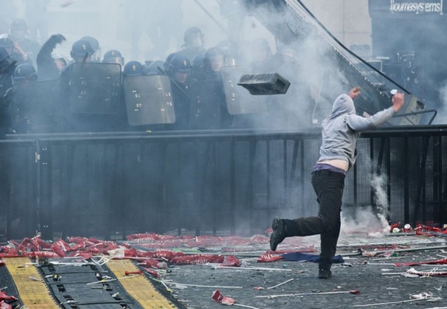 A fan throws debris at riot police in the clash between rioters and police forces during the PSG title celebration-football